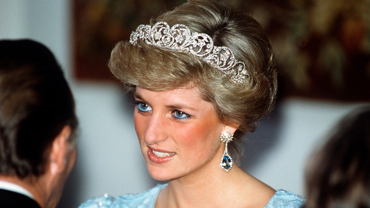 A close-up of Princess Diana wearing a tiara talking to a man.
