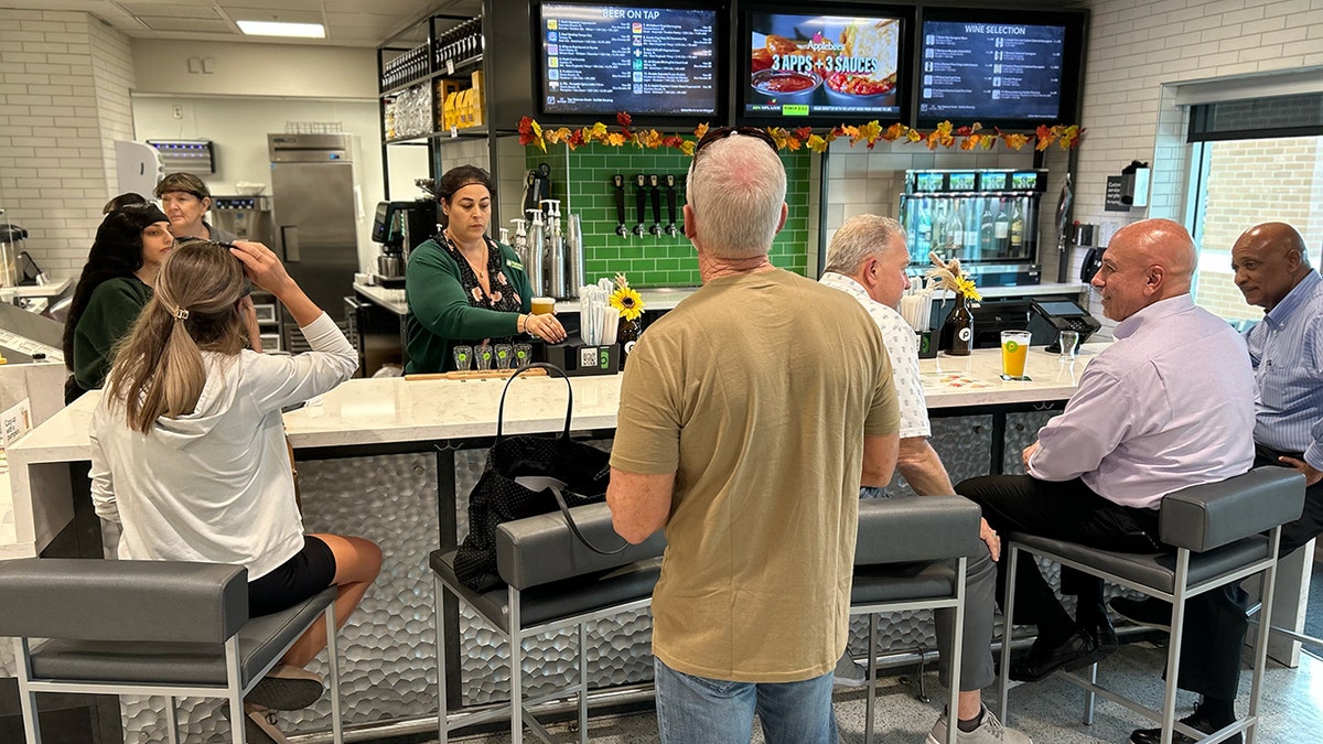 A Publix Pours bar with customers and bartenders is shown.
