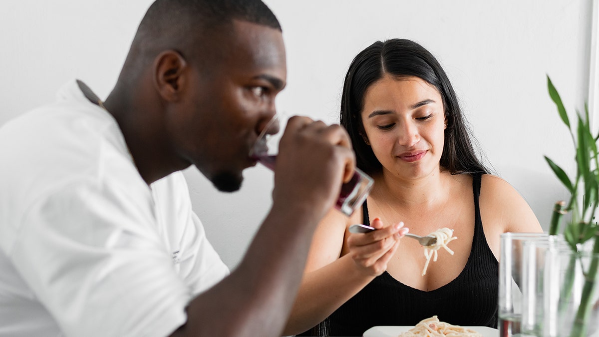 Young couple eating spaghetti at table