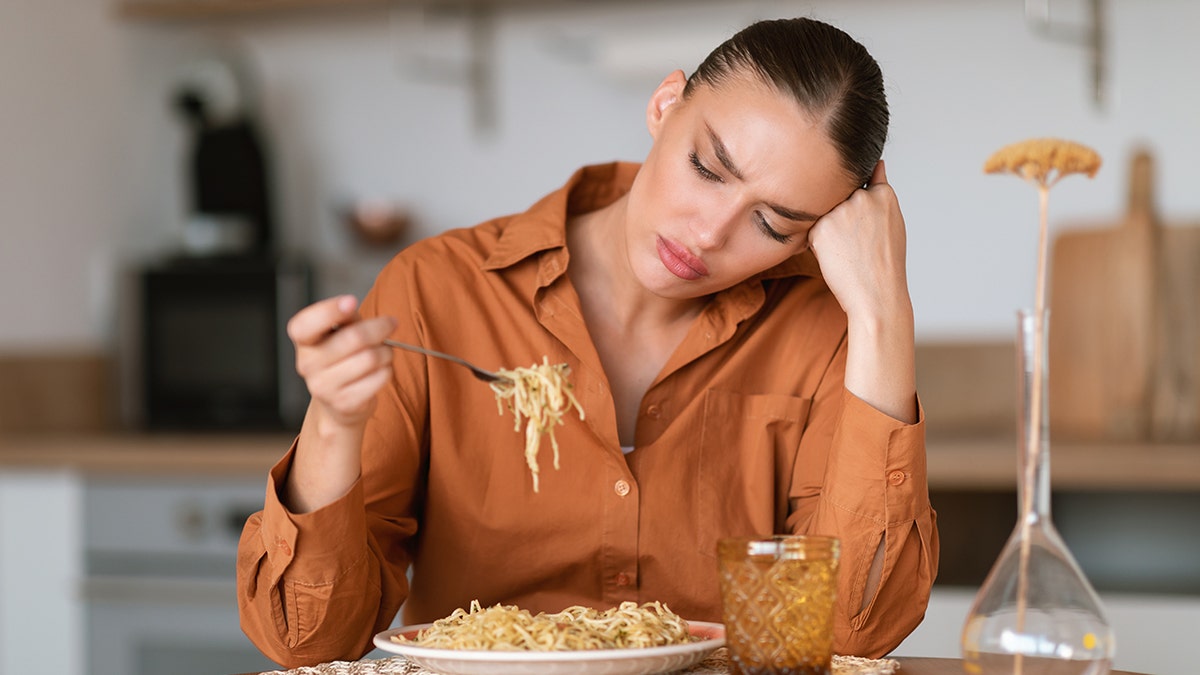 Annoyed woman eating spaghetti