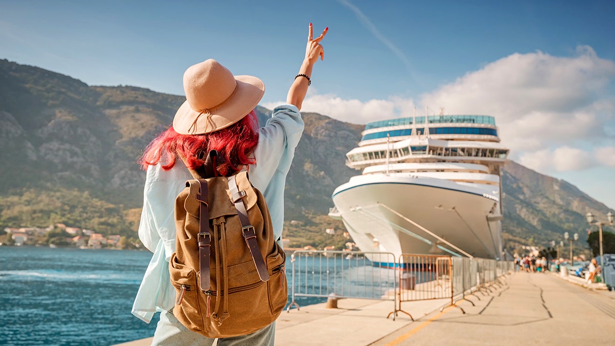 A tourist wearing a backpack and hatred of the hat near the cruise ship