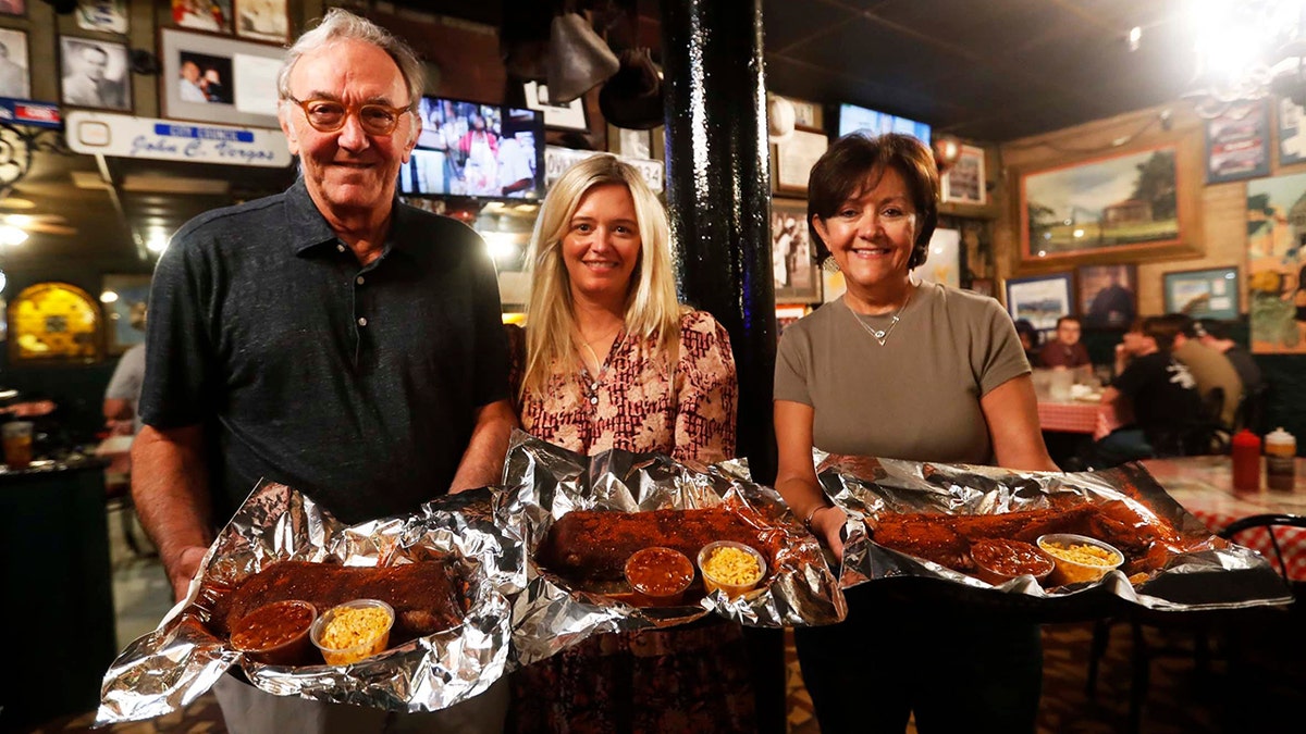 The co-owners of the Rendezvous restaurant in downtown Memphis hold barbecue ribs on plates.