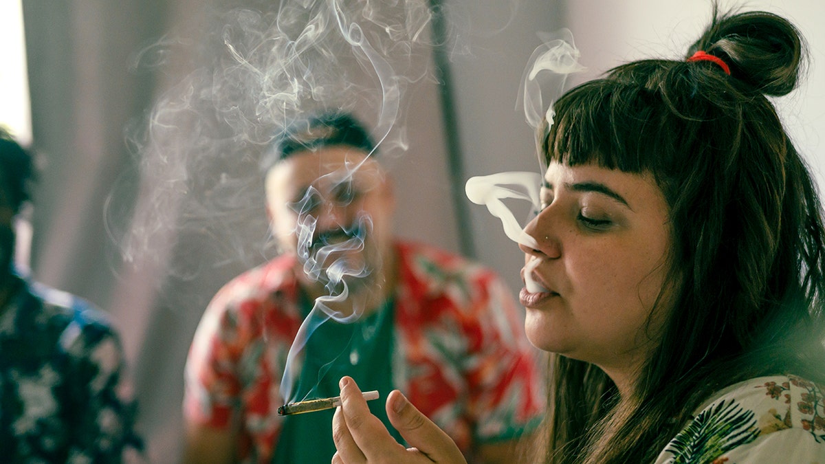 Woman smoking marijuana and letting out smoke