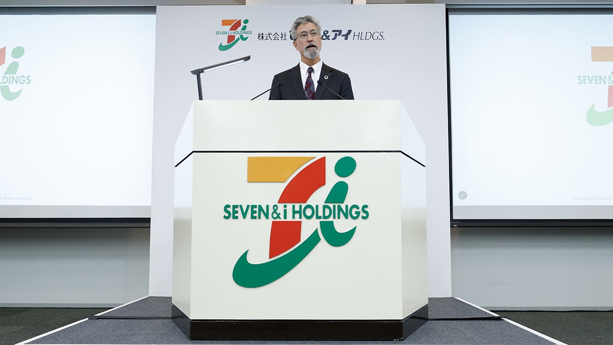 Stephen Dacus, chief executive officer of Seven & i Holdings Co., speaking at branded podium during a news conference in Tokyo, Japan, on Thursday, March 6, 2025.