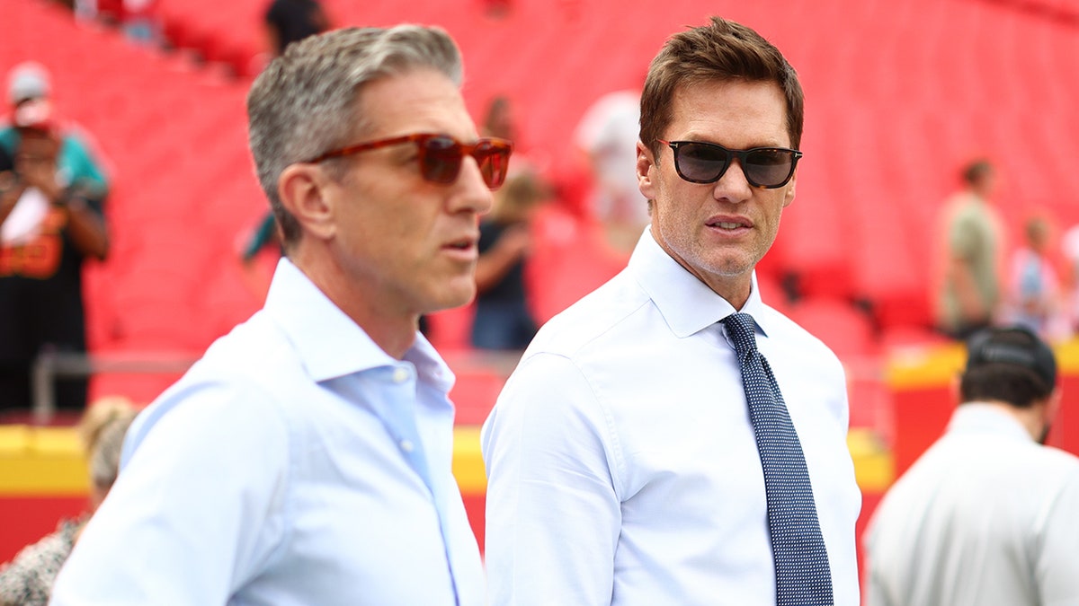 Tom Brady and Kevin Burkhardt look on field together