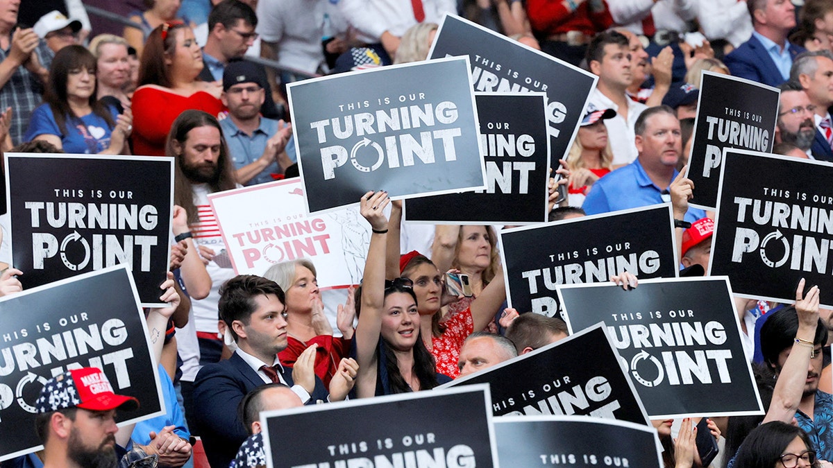 People hold "This is our Turning Point" signs during a memorial for Charlie Kirk