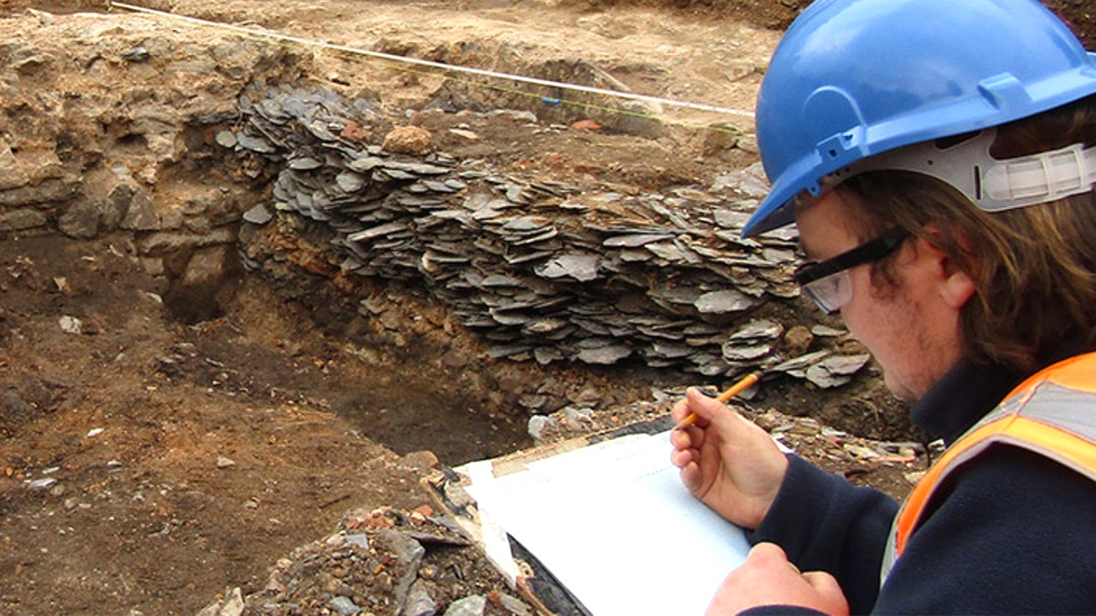 Archaeologist writing on pad at excavation site