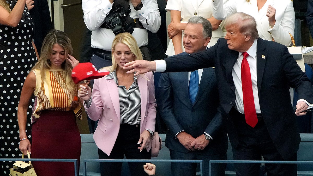 Donald Trump tosses a hat back