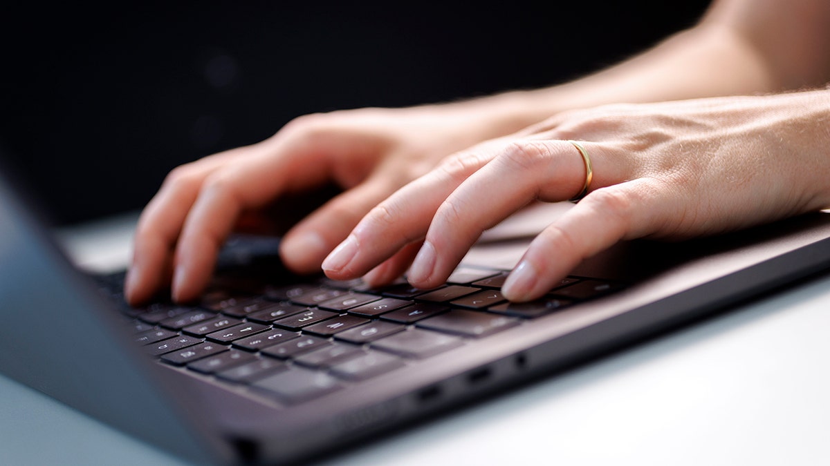 Woman typing on a laptop.