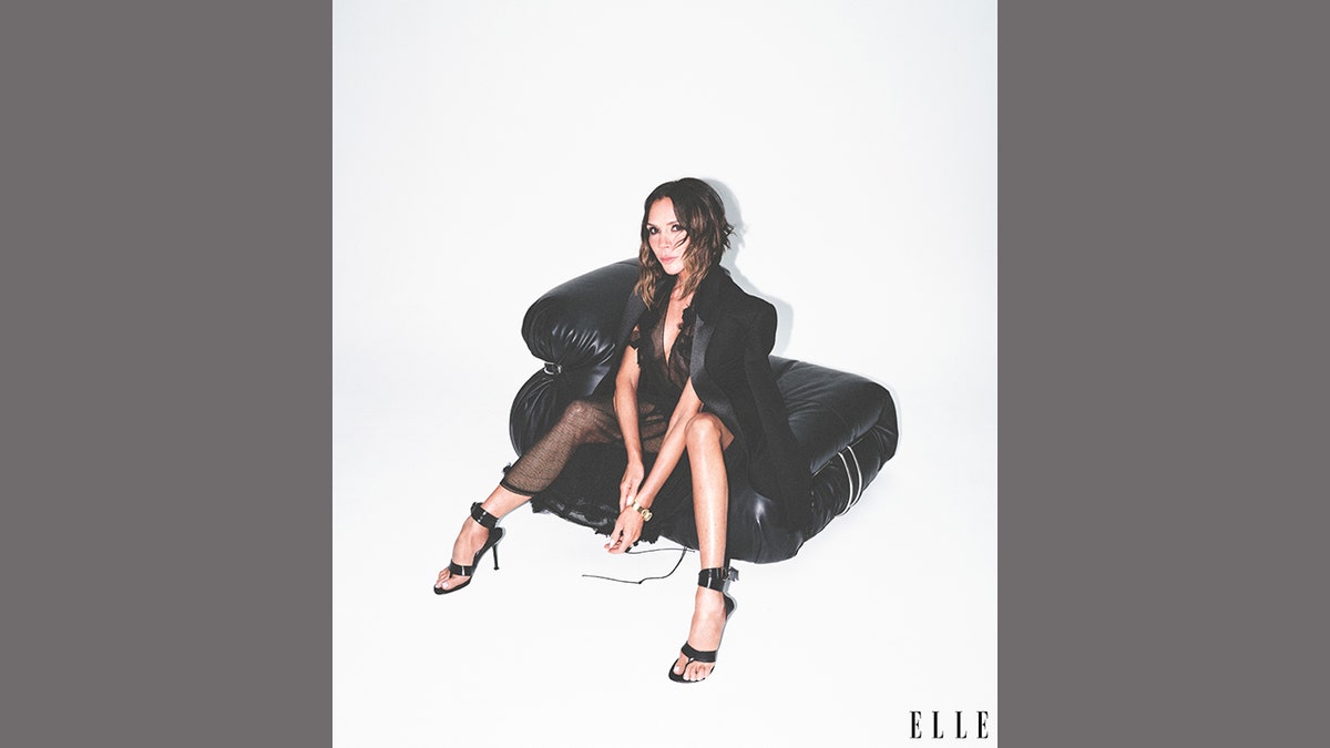 Victoria Beckham posing on a a couch in black