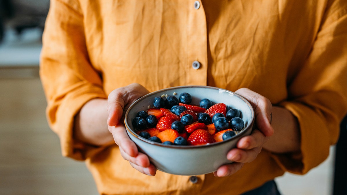 Women carry a bowl of berries