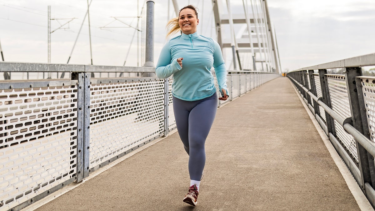 A slightly overweight young woman goes jogging on the bridge