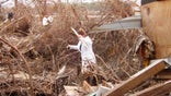 Woman walks through storm debris after Hurricane Katrina in Buras, LA.
