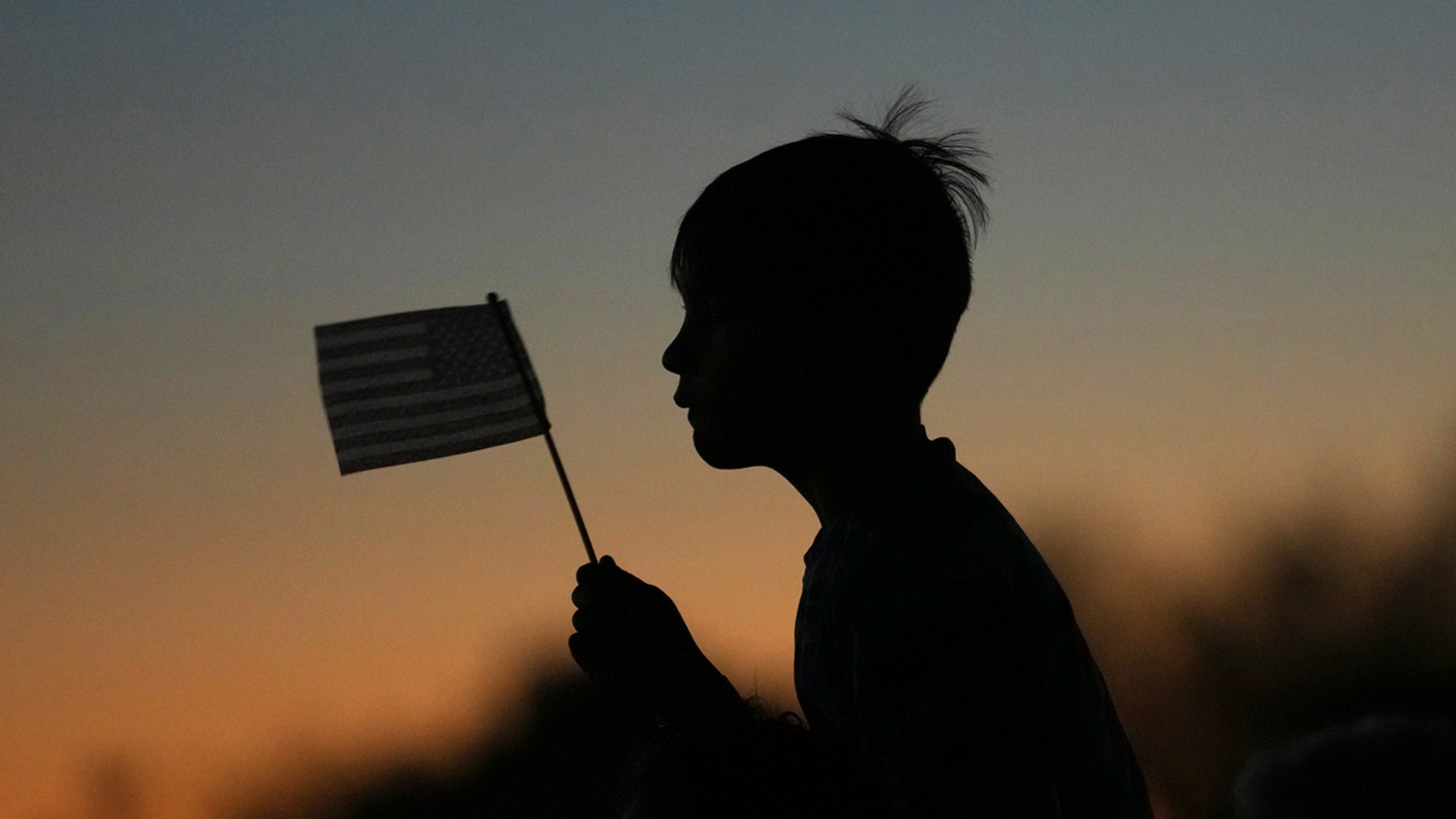 Boy waves flag at Charlie Kirk vigil
