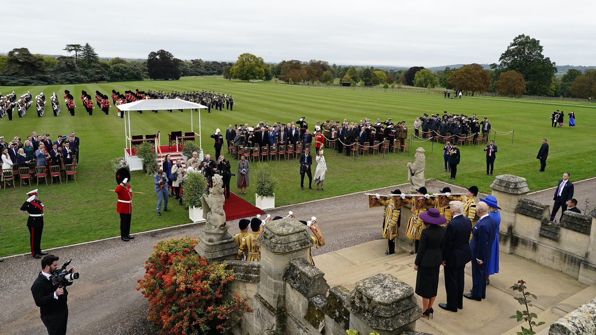Wide overhead view of Windsor Castle’s ceremonial lawns with marching guards, guests, and royals including Donald Trump.