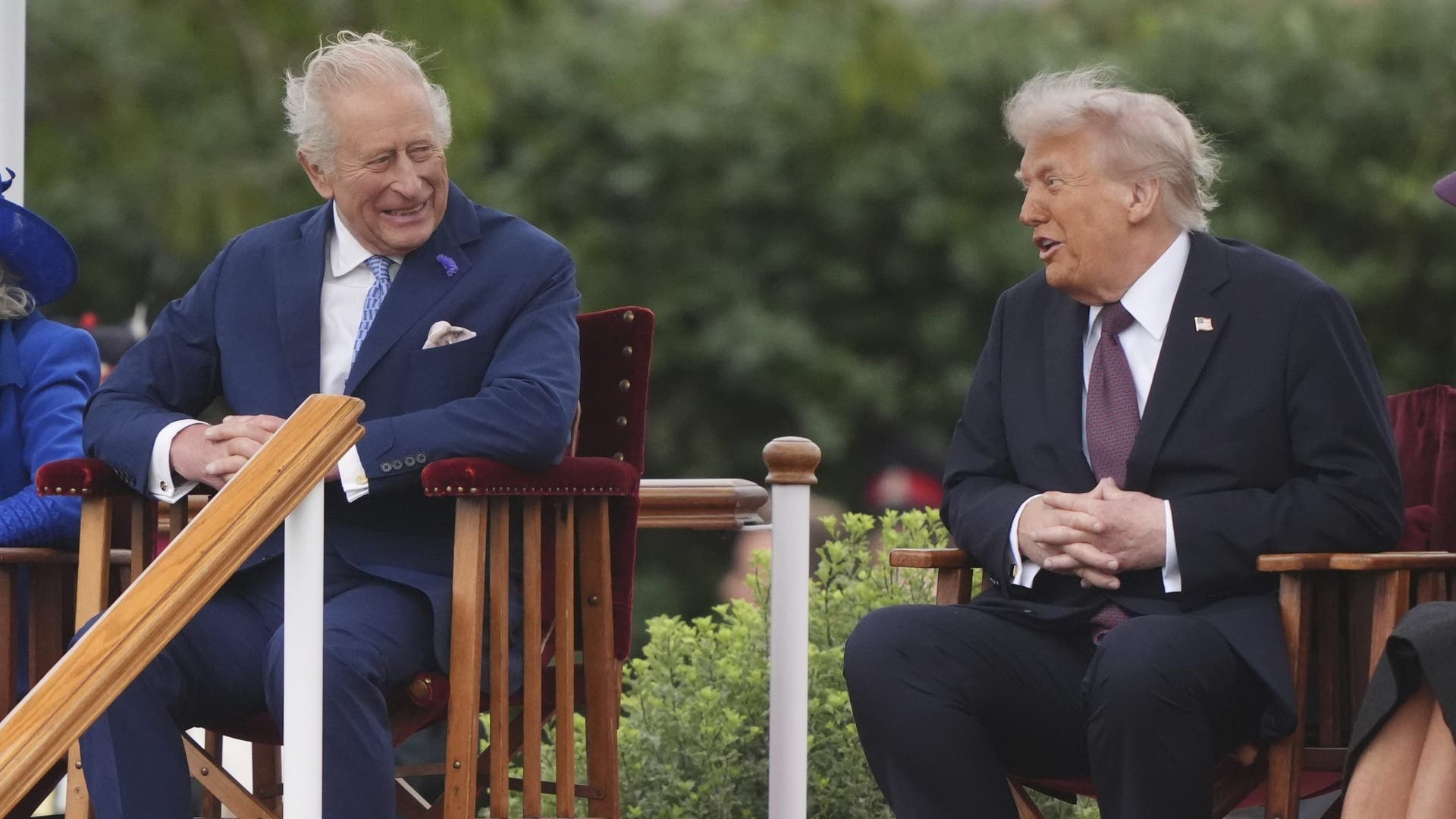 King Charles III smiles while seated next to Donald Trump, who gestures during their conversation at Windsor Castle.