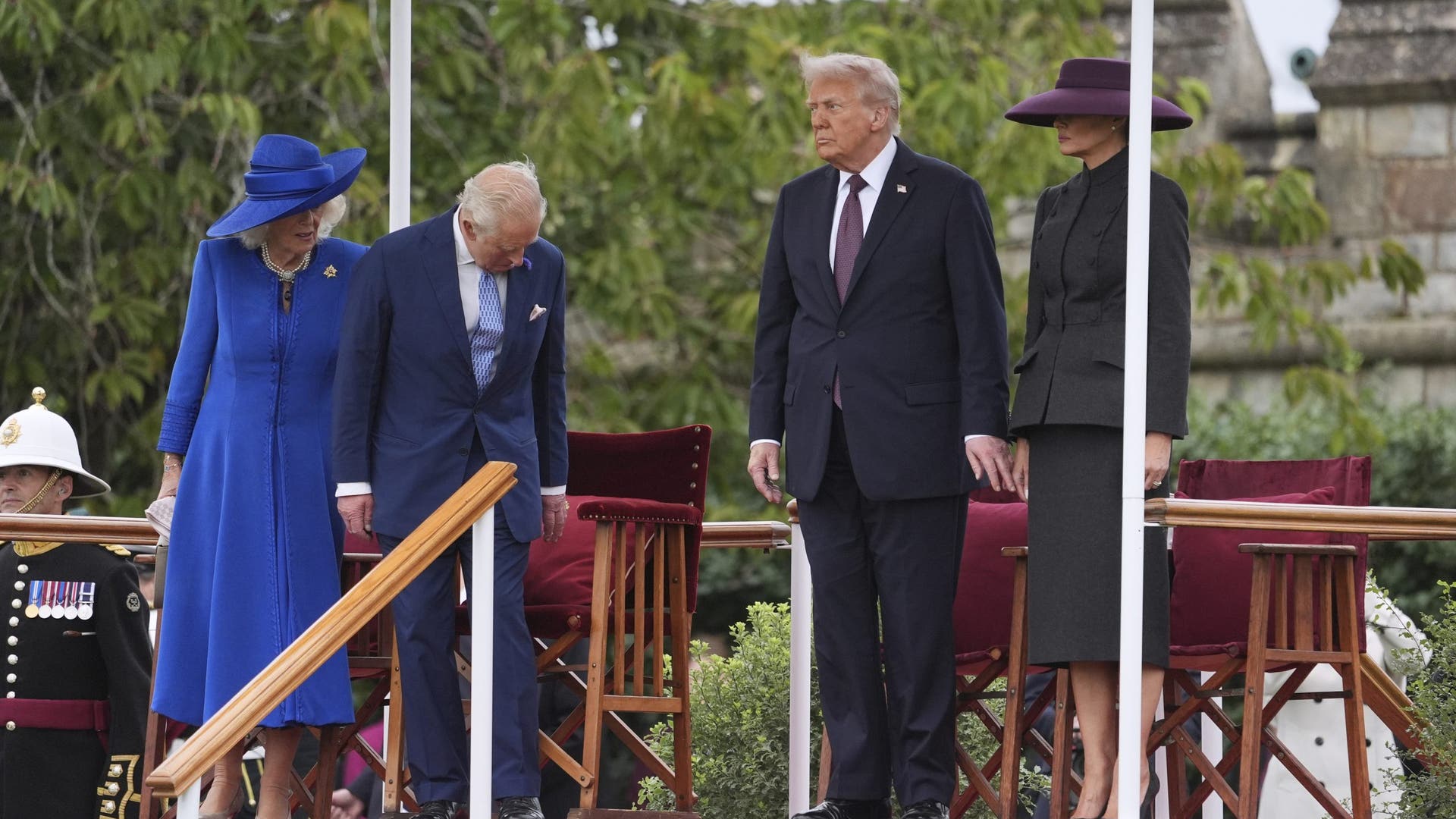British guards march across the parade field while King Charles, Queen Camilla, Donald Trump, and Melania Trump observe from their seats.