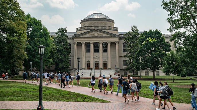 A line of students walk on the campus of the University of North Carolina