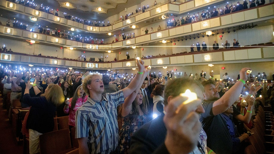 People hold candles and sing during Charlie Kirk vigil