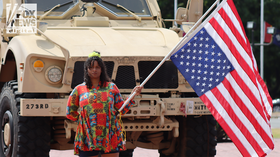 protester with upside down stands in front of national guard truck