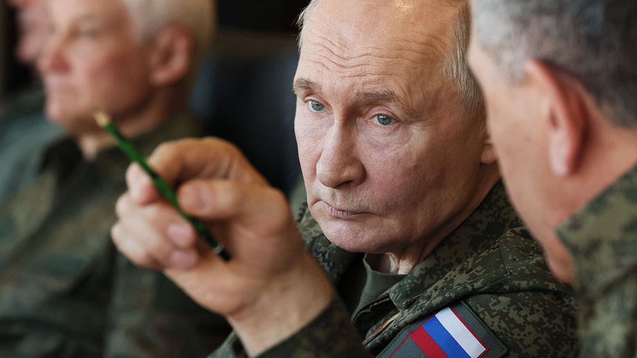 Vladimir Putin looks on while being surrounded by military members