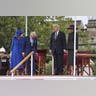 British guards march across the parade field while King Charles, Queen Camilla, Donald Trump, and Melania Trump observe from their seats.