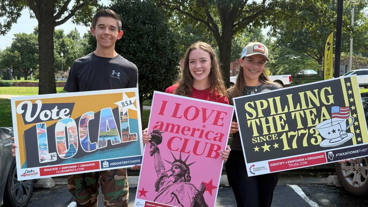 Teenagers holding signs supporting Turning Point USA and American values