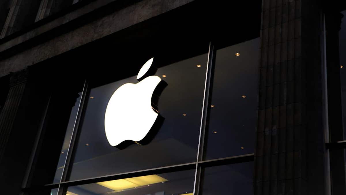 Apple logo glows on the front of an Apple Store building at night.