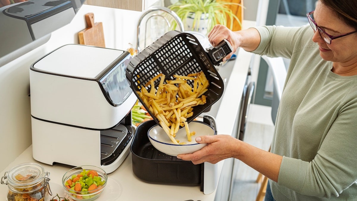A woman cooking fried potatoes in the air frying pan