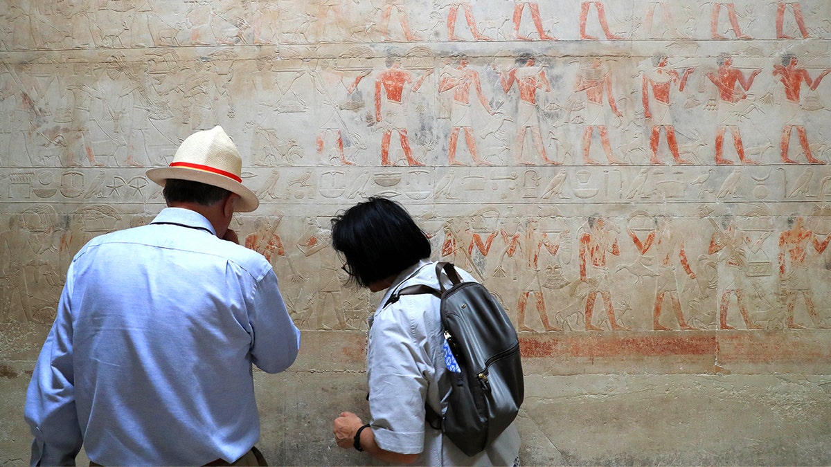 Tourists looking at painting in necropolis
