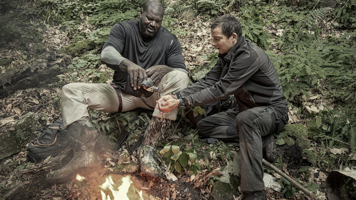 Bear Grylls duduk di dekat api unggun bersama legenda NBA Shaquille O'Neal