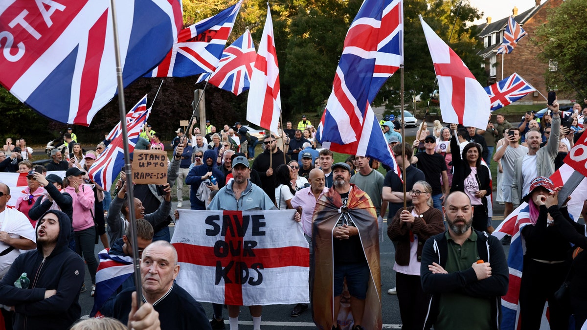 Protesters hold British flags and signs at an anti-immigration protest in Epping