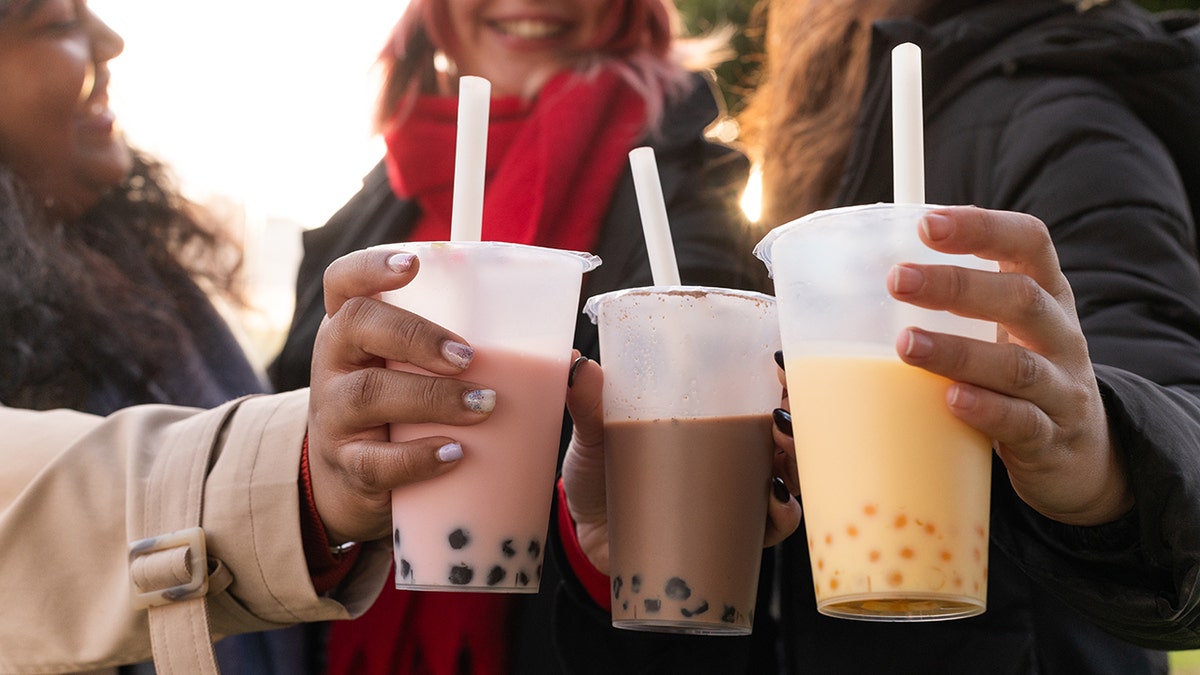 Tiga orang teman menyajikan bubble tea dengan warna berbeda
