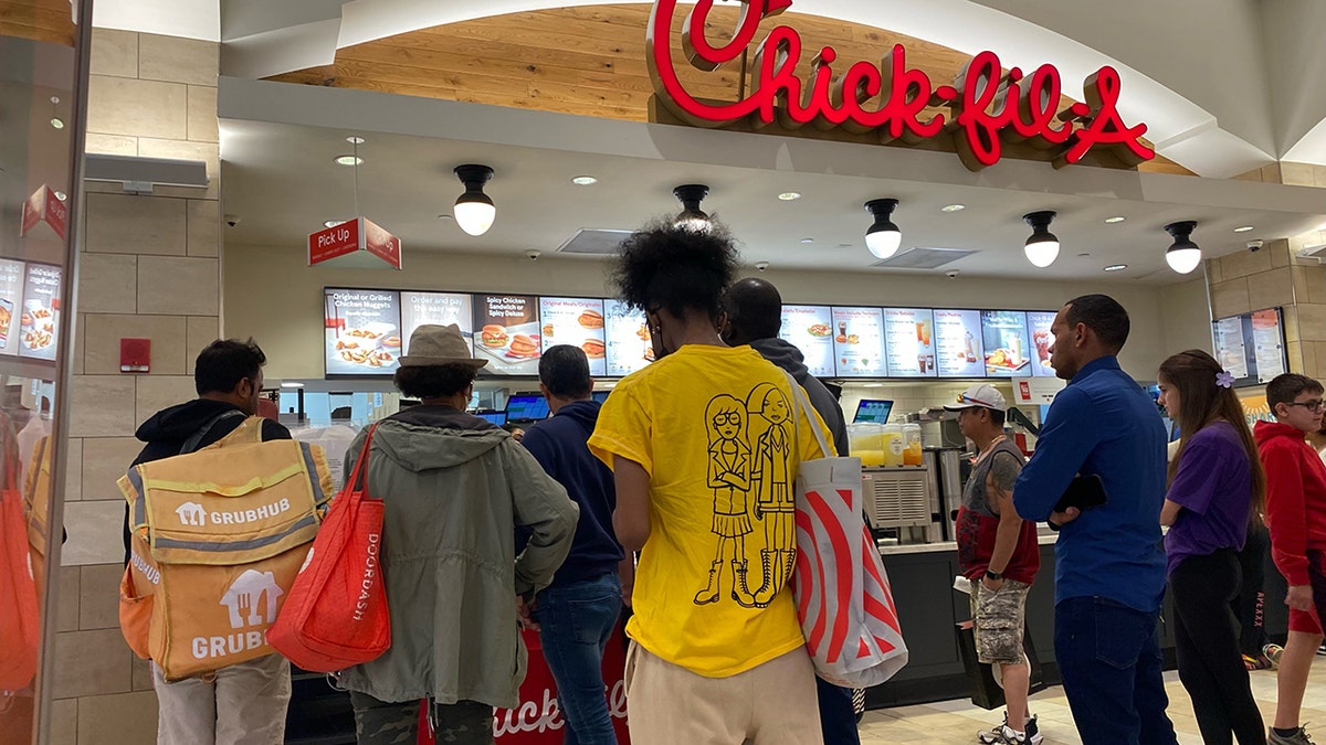People waiting at and ordering at Chick-fil-A counter in Queens, New York.