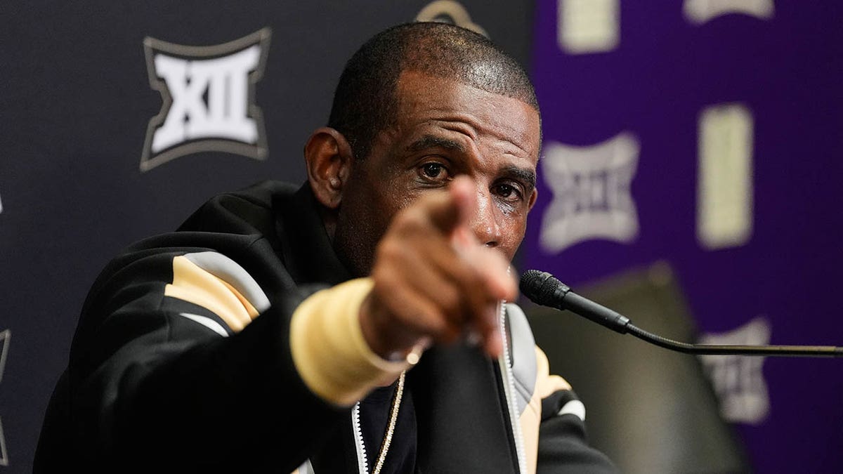 Deion Sanders points to a reporter