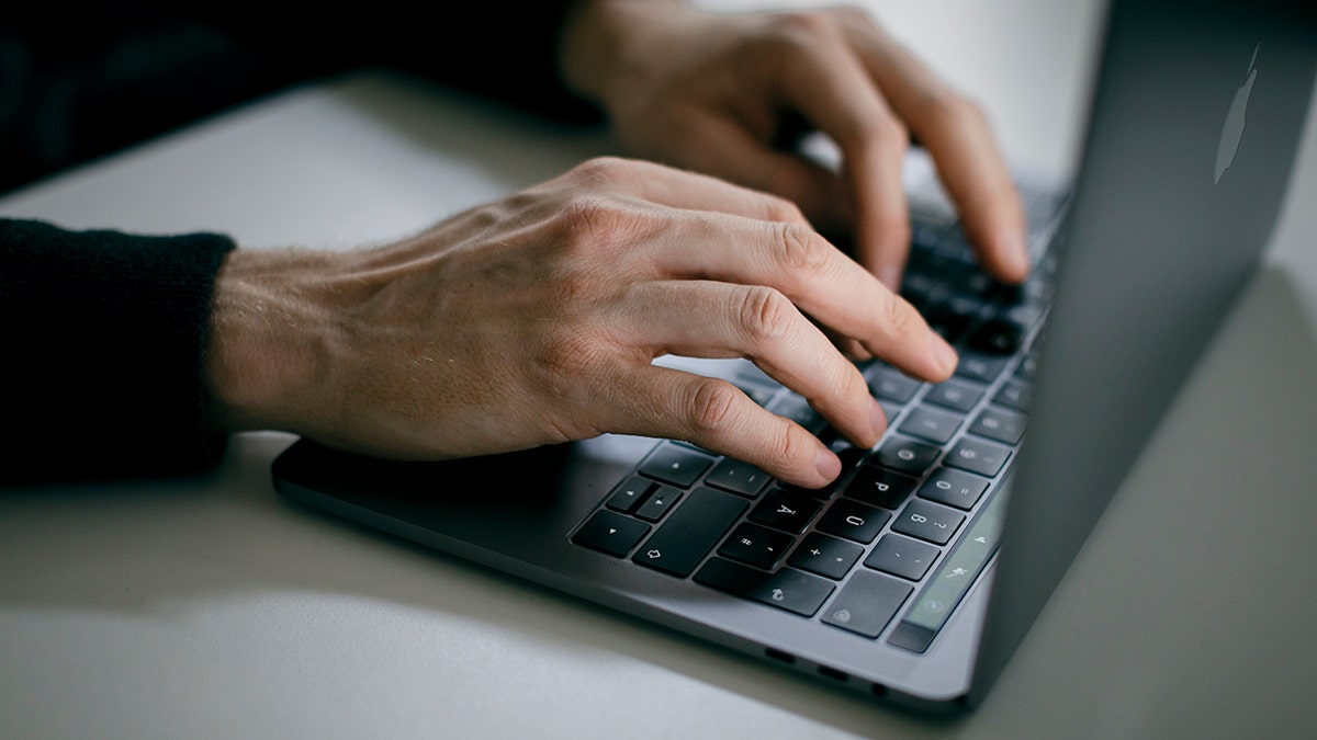 A man writes on his laptop.