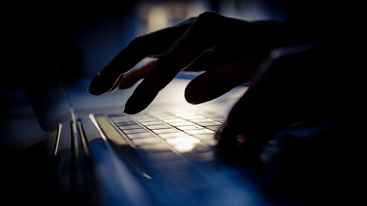 A hacker is typing on his laptop.
