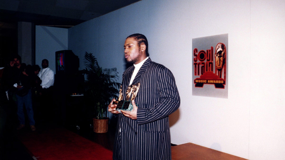 D'Angelo stands with an award while taking a photo