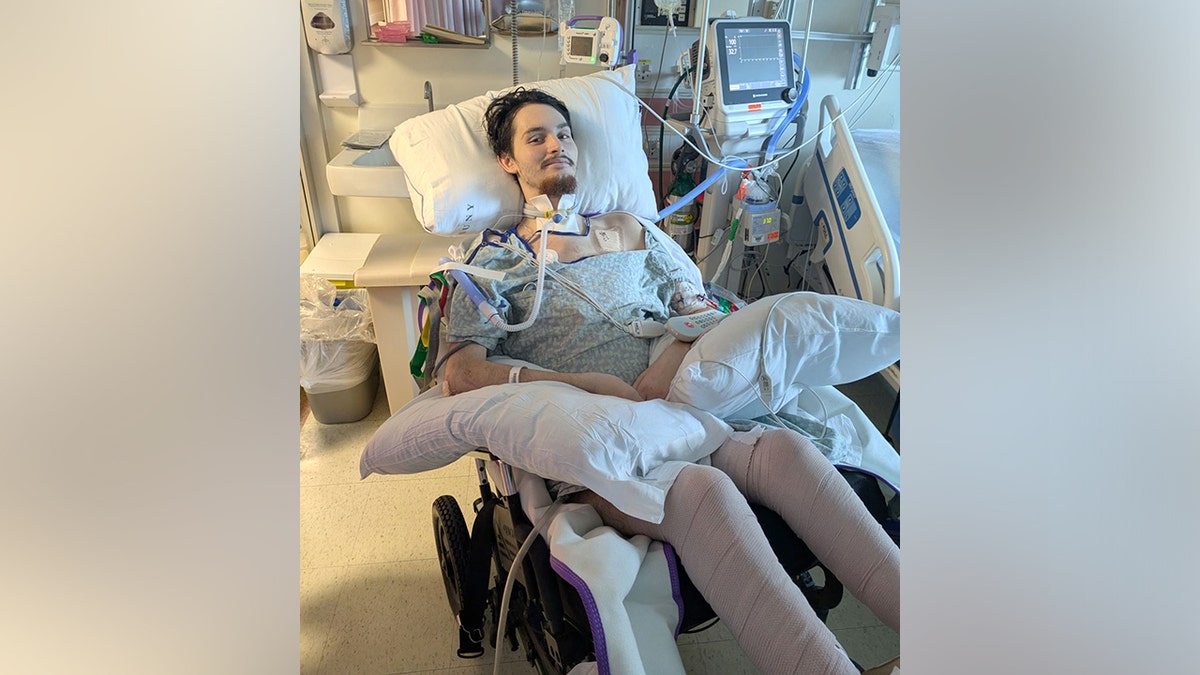Daniel Waterman smiling in hospital bed as he's hooked up to various machines