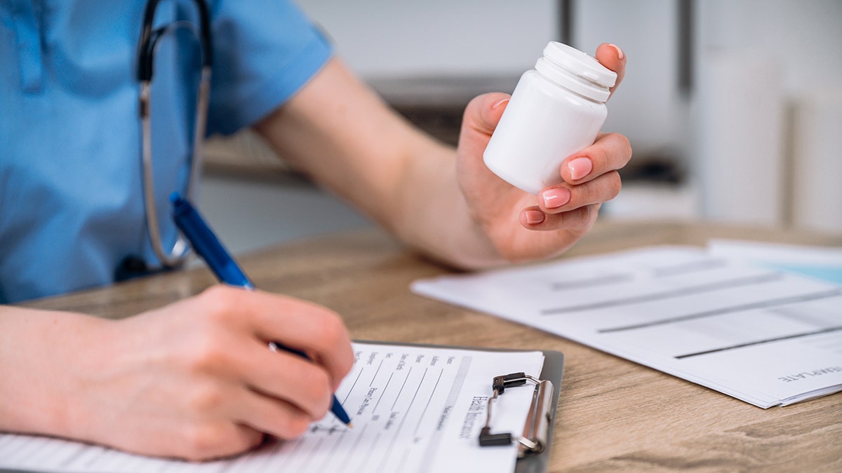 Selective focus on bottle with medication prescribing to sick patient.