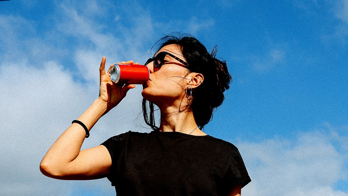 Woman on a road trip having a quick break at the gas station drinking soda