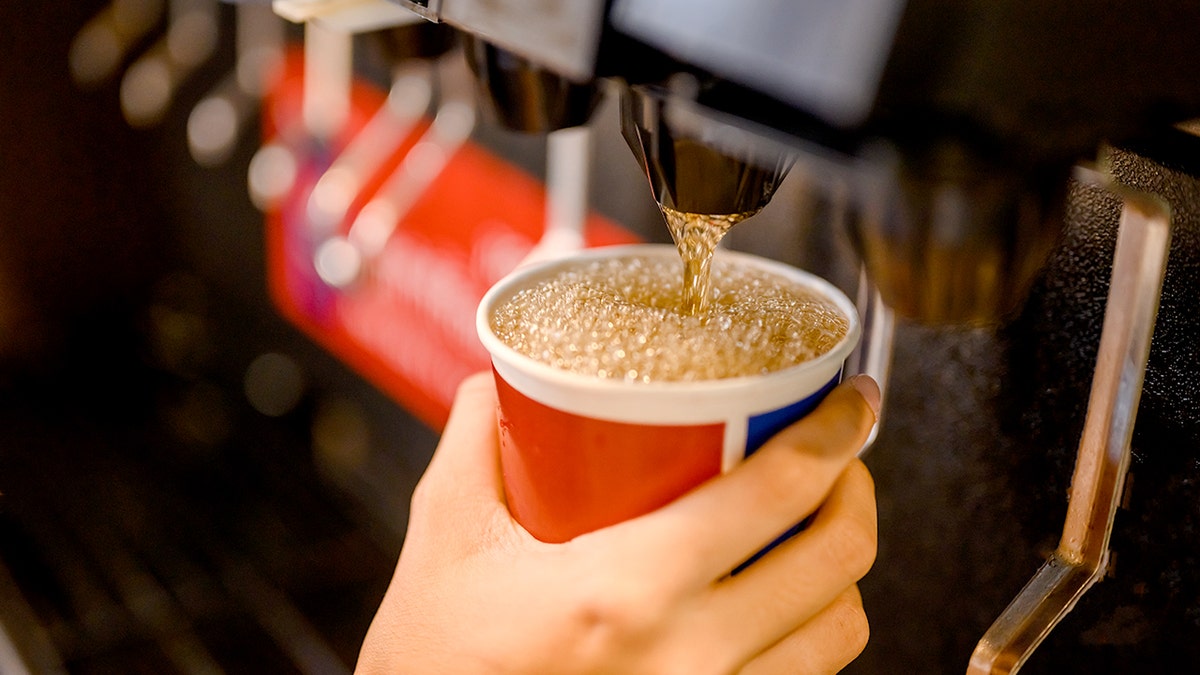 man pours a fizzy drink