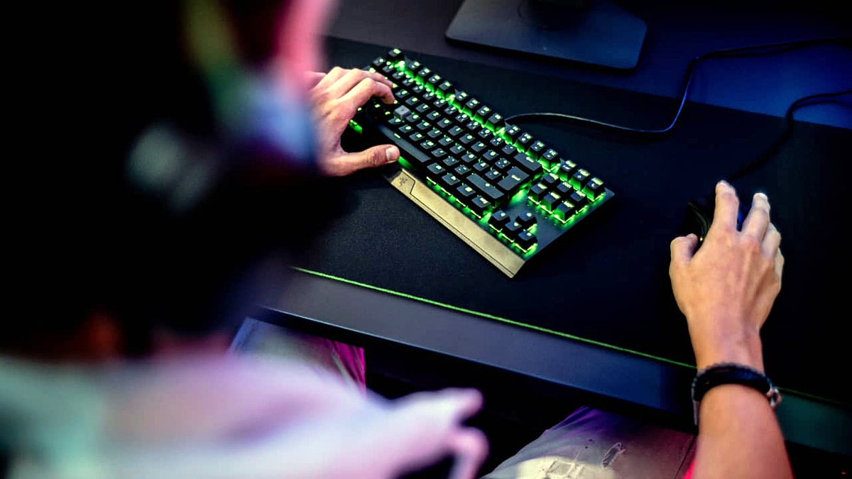 Um homem digitando em um teclado de jogo