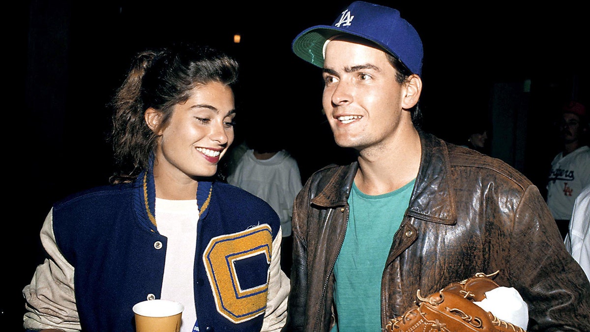 Dolly Fox smiling as she walks next to Charlie Sheen.