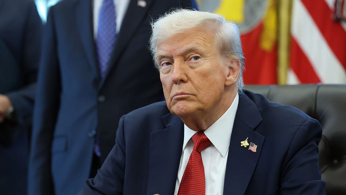 O presidente Donald Trump está sentado em sua mesa no escritório oval