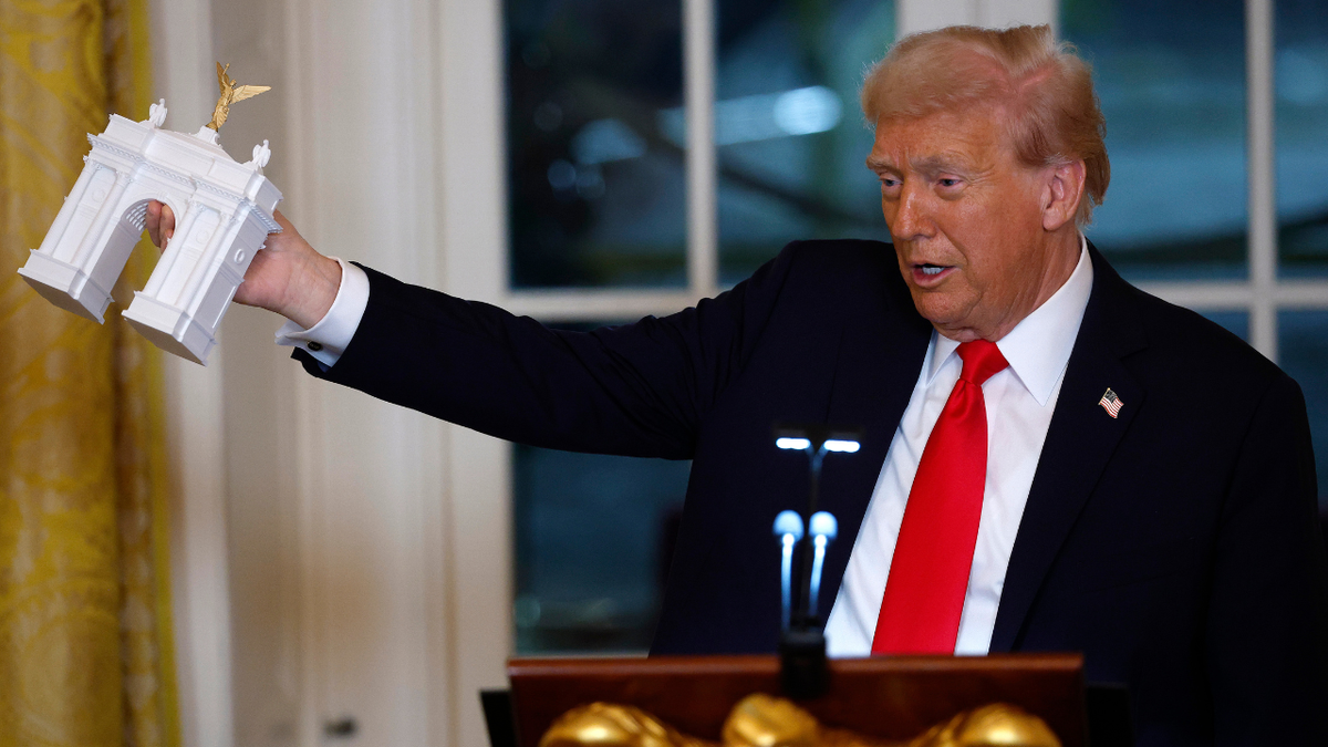 U.S. President Donald Trump holds a model of a new arch