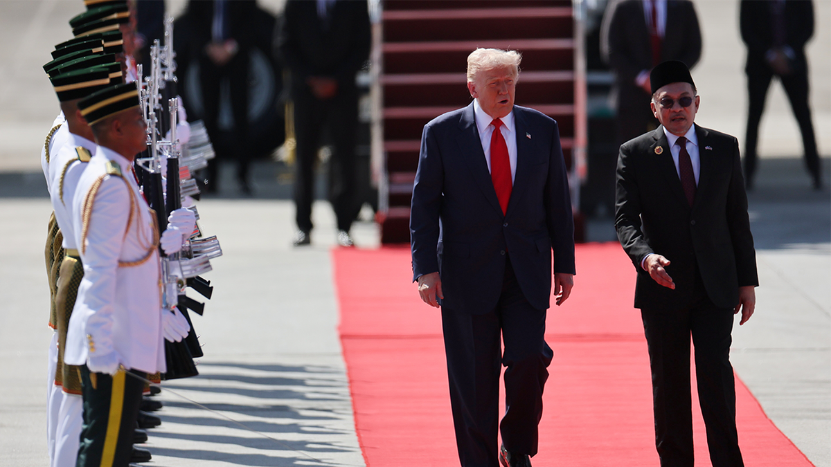 U.S. President Donald Trump walks with Malaysian Prime Minister Anwar Ibrahim as he arrives at Kuala Lumpur International Airport