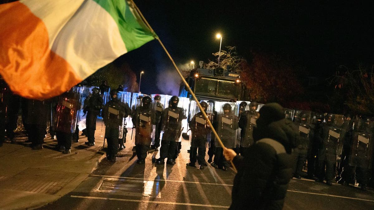 Protesters wave the Irish flag in front of riot police during a Dublin protest.