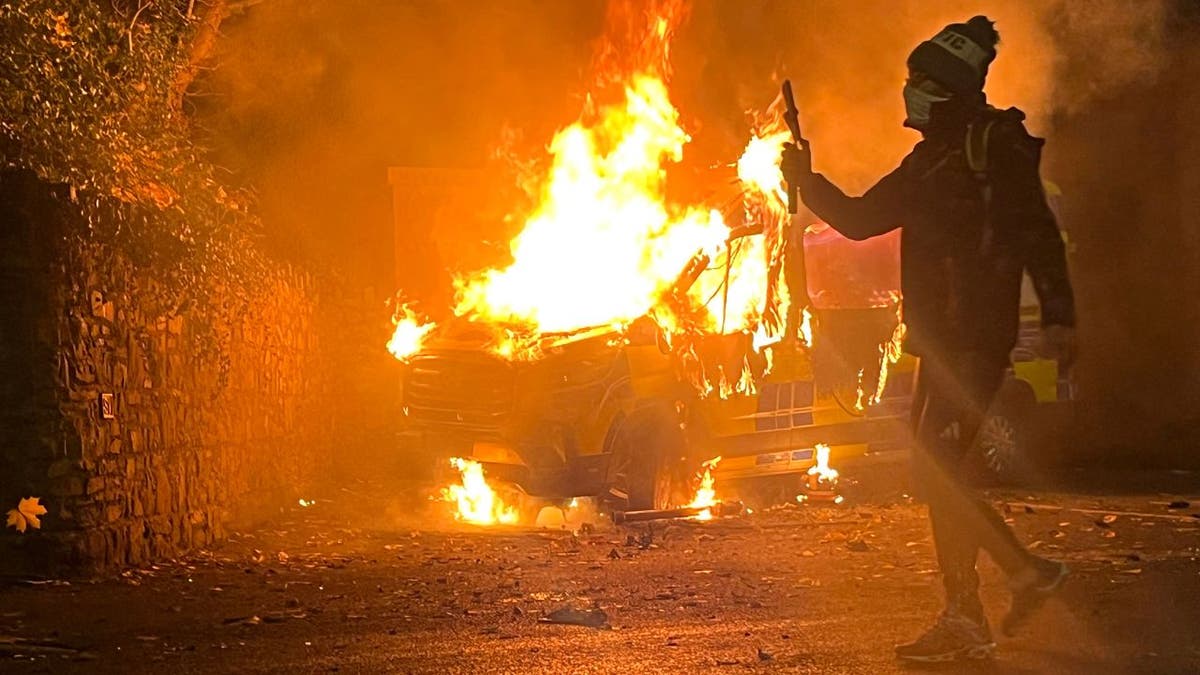 Films the protest as a Garda car catches fire during a violent protest.