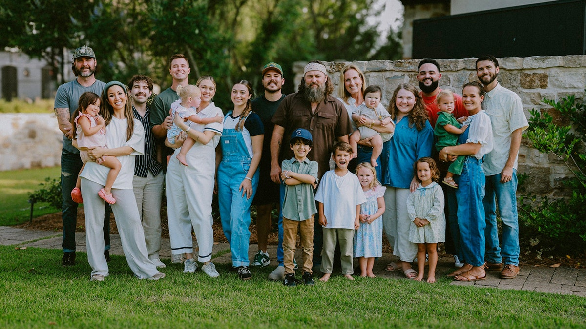 "Duck Dynasty" family group posing together outdoors, including adults and children.